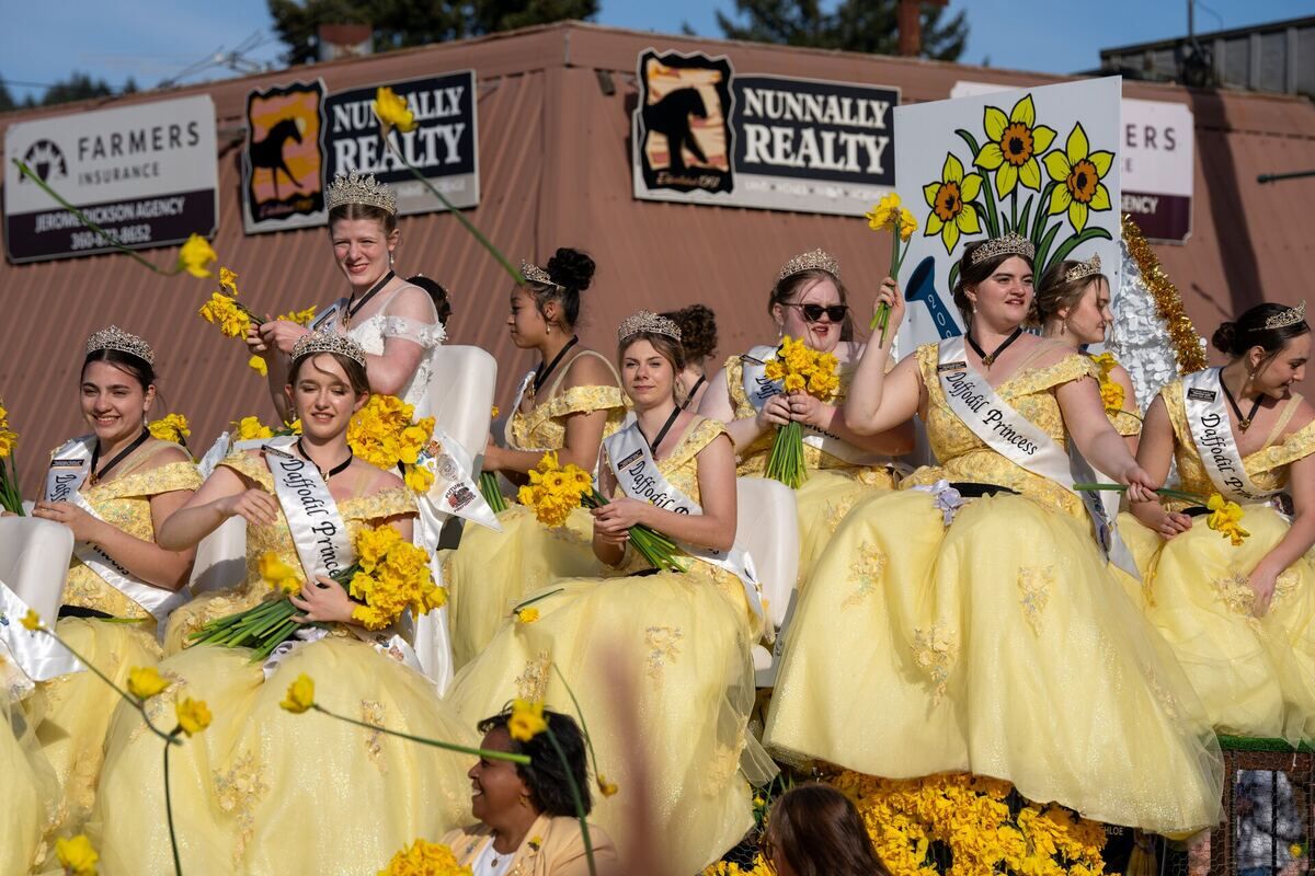 Daffodil princesses in yellow gowns wave daffodils from a float